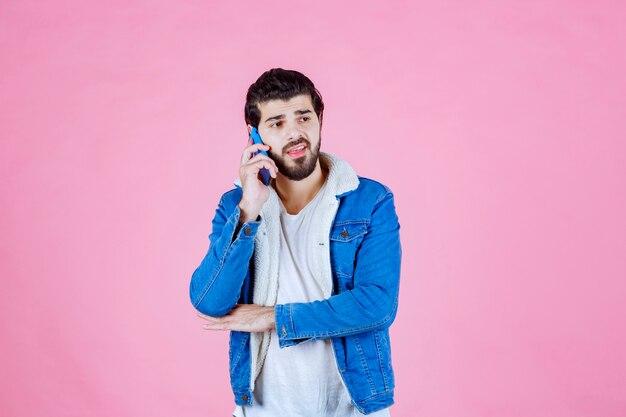 Uomo in giacca di jeans, parlando al telefono cellulare.