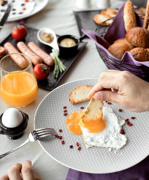 Man dipping roast into egg yellow for breakfast