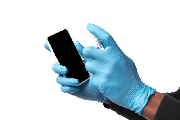 Man disinfecting gadgets on white wall