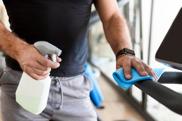 Man disinfecting gym equipment