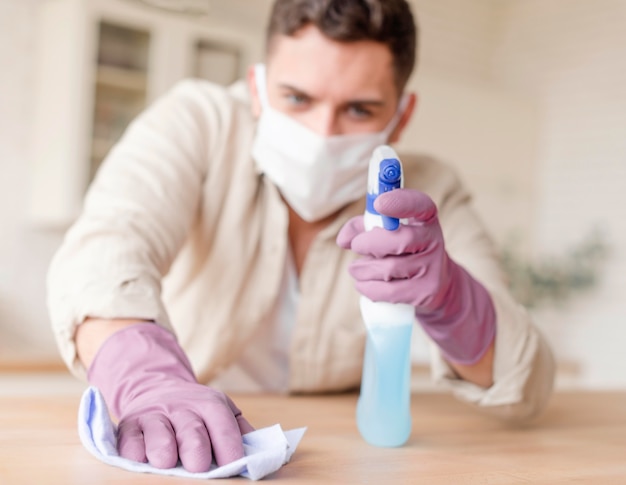 Free photo man disinfecting wooden table