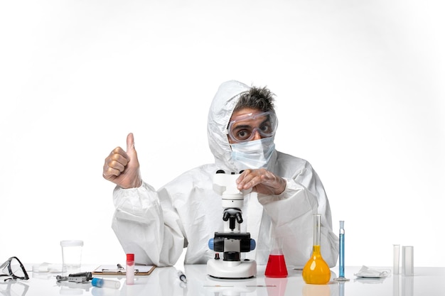 man doctor in protective suit and mask using his microscope on light white
