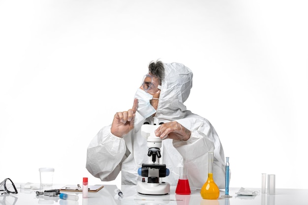 man doctor in protective suit and mask using microscope on light white