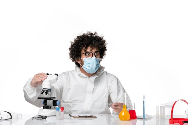 man doctor in protective suit and mask using microscope on white