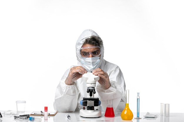 man doctor in protective suit and mask using microscope on white