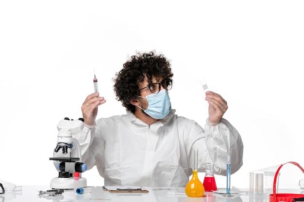 человек-врач в защитном костюме и маске, работающий с инъекциями на белом