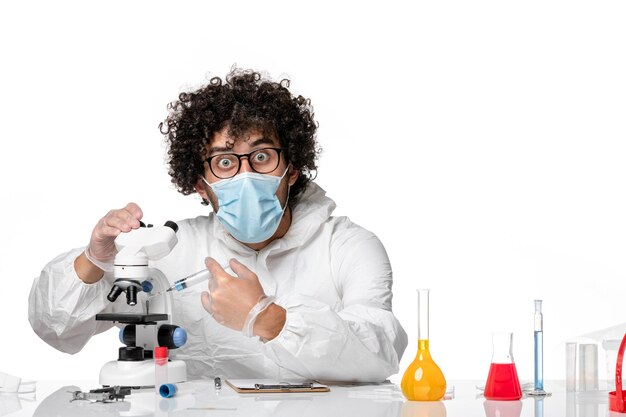 man doctor in protective suit and mask working with microscope on light white