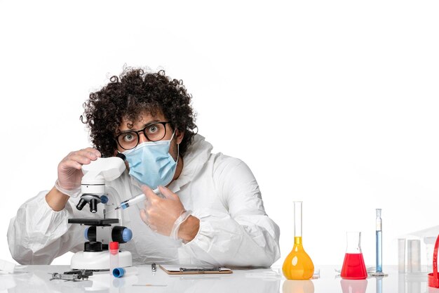man doctor in protective suit and mask working with microscope on white