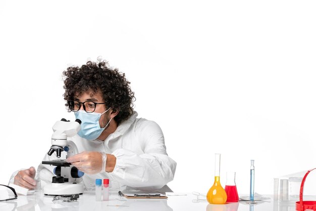 man doctor in protective suit sterile mask holding sample and using microscope on white