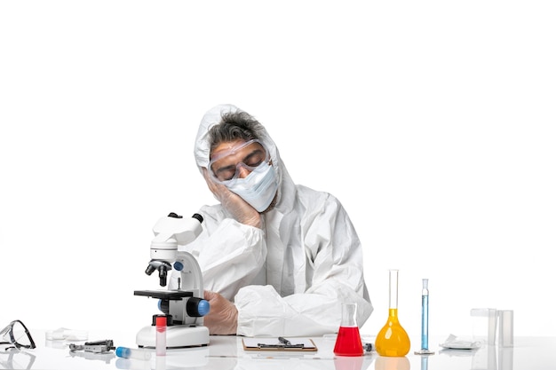 man doctor in protective suit and with mask sitting and tired on white