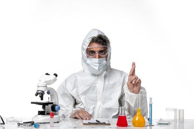 man doctor in protective suit with sterile mask crossing his fingers on white