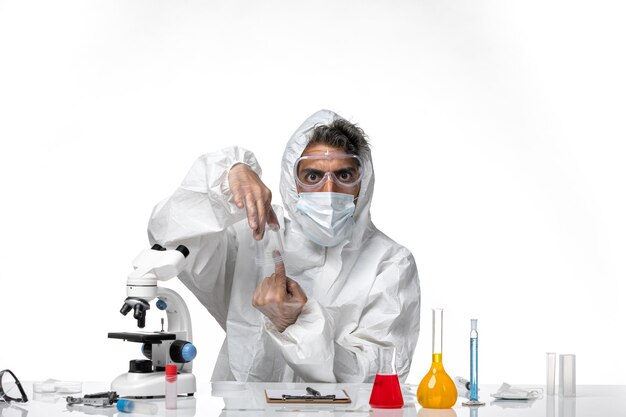 мужчина-врач в защитном костюме и стерильной маске держит пустую фляжку на белом