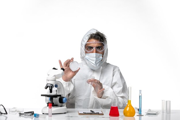 man doctor in protective suit and with sterile mask holding flask on white