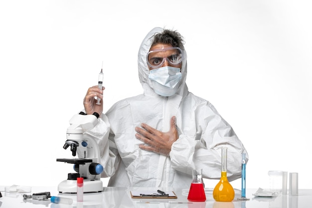 man doctor in protective suit with sterile mask holding injection on a white