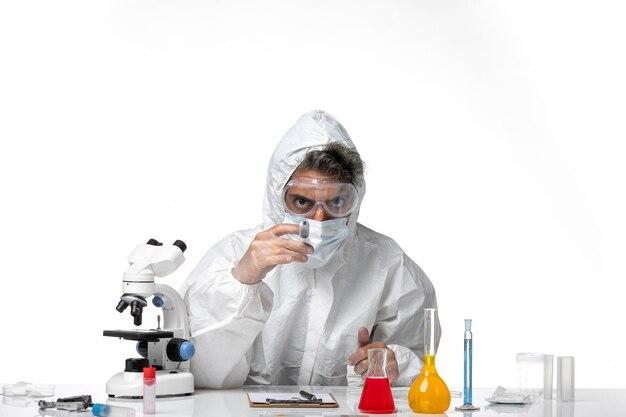 man doctor in protective suit with sterile mask holding injection on a white