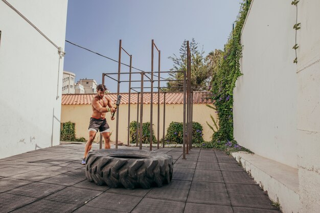Man doing crossfit with wheel and hammer