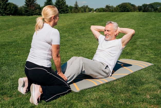 Man doing crunches and being held by woman