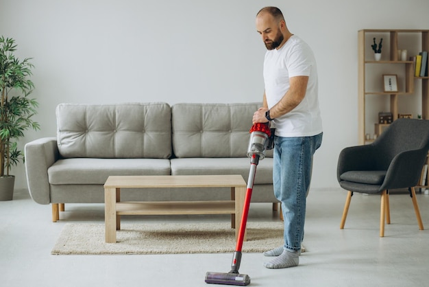 Man doing house work with accumulator vacuum cleaner