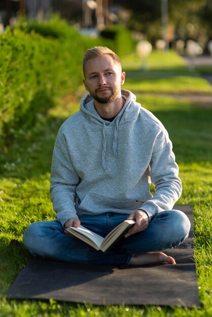 Man doing the lotus position while holding a book