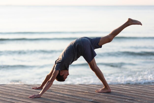 Man doing one legged downward dog pose outside