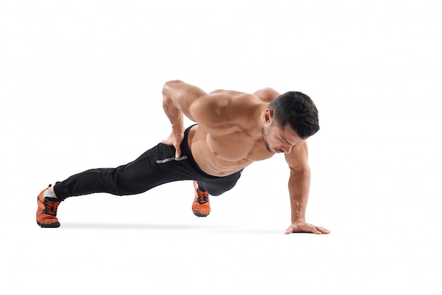 Free photo man doing plank exercise on one hand.