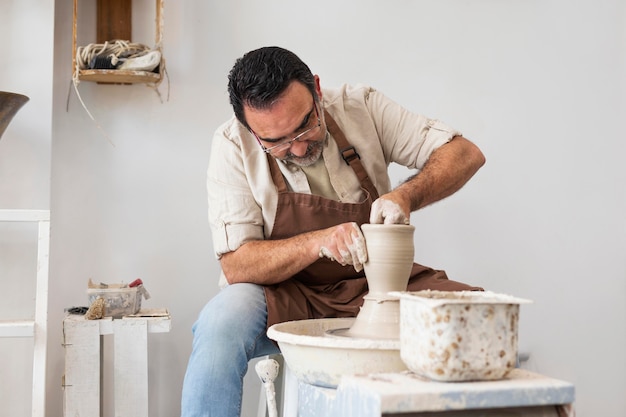 Man doing pottery indoors medium shot