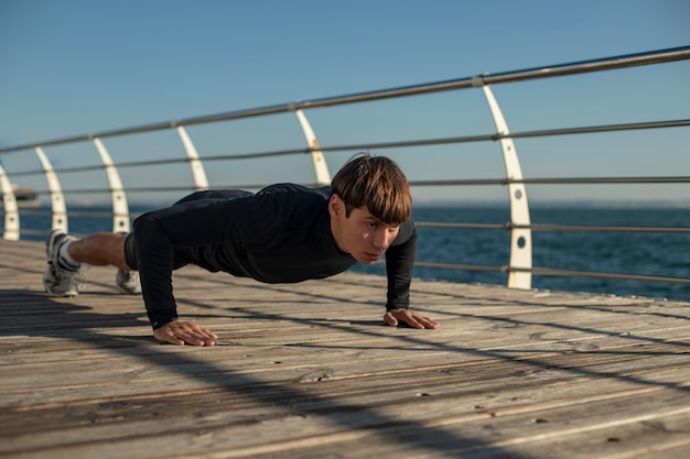 Man doing push-ups in activewear by the beach