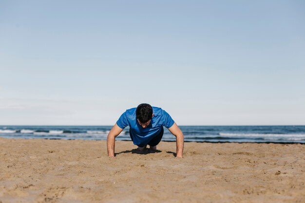 Man doing push ups at beach