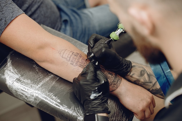 Free photo man doing a tattoo in a tattoo salon