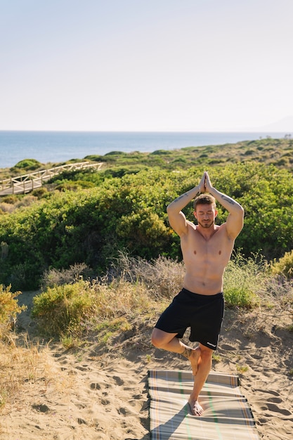 Человек делает йогу на пляже