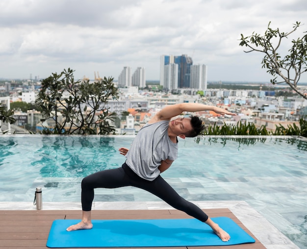 Man doing yoga outdoors by the pool