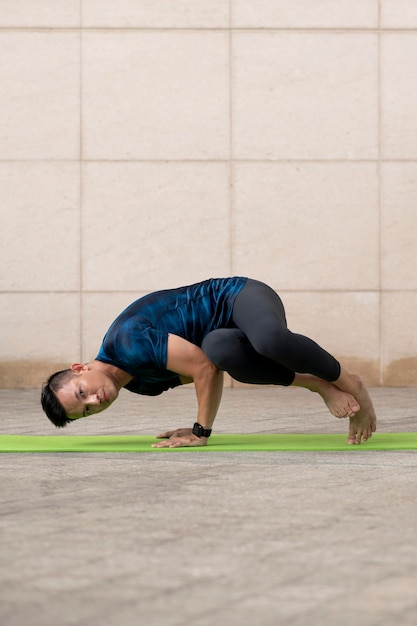 Foto gratuita uomo che fa yoga all'aperto sulla stuoia