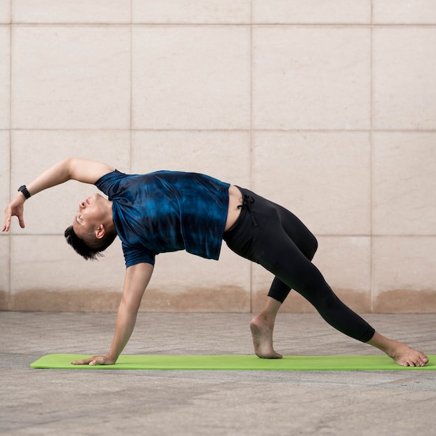 Uomo che fa yoga fuori sulla stuoia con copia spazio