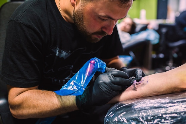 Man drawing with tattoo pen on arm