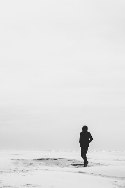 A man dressed in all black walking in a plain white surface