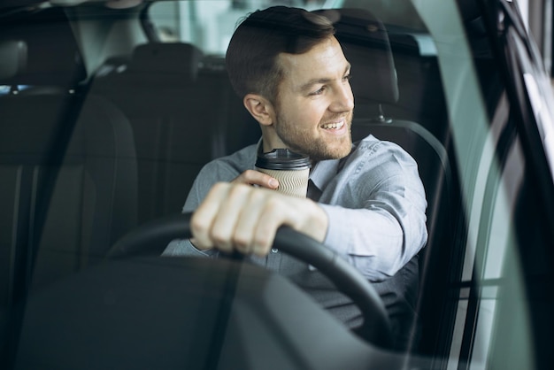 無料写真 コーヒーを飲み、車を運転する男