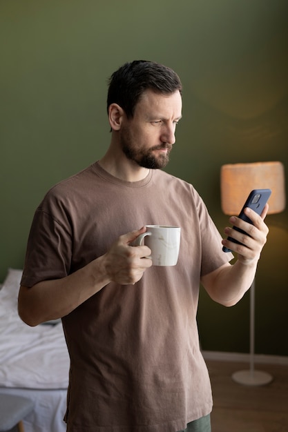 コーヒーを飲み、スマートフォンでメールをチェックする男