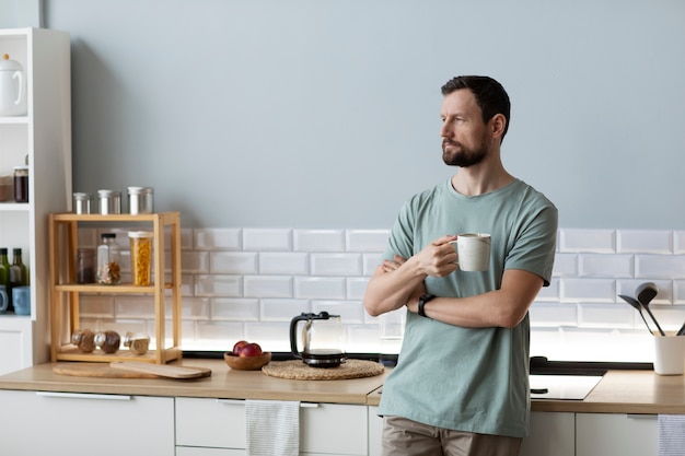Foto gratuita uomo che beve caffè in cucina