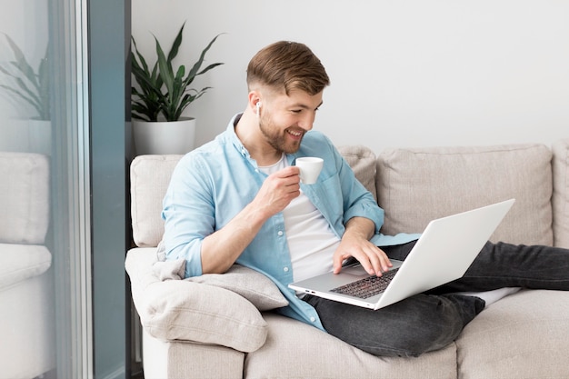 Man drinking coffee and using laptop