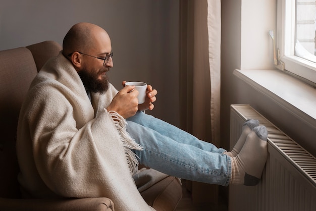 Мужчина пьет горячий напиток во время энергетического кризиса