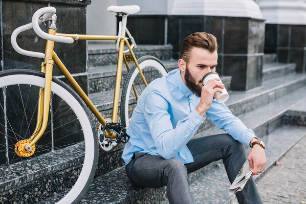 Man drinking hot beverage on stairs