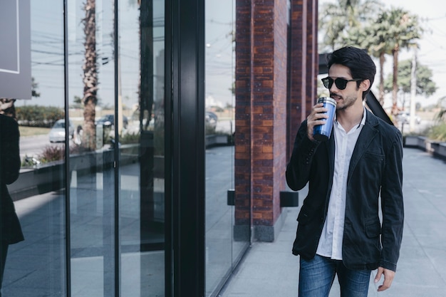 Man drinking near glass wall