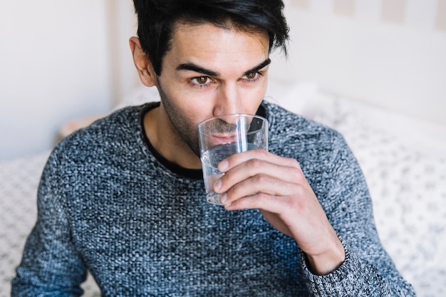 Man drinking water on bed