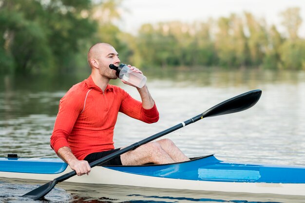 Мужчина пьет воду в каяке