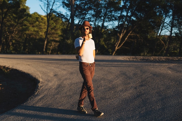 Free photo man drinking while walking in countryside