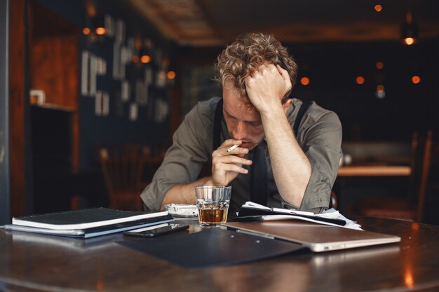 Man drinks whiskey. Businessman reads documents. Director in a shirt and suspenders.