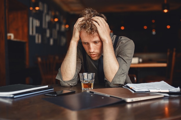 Free photo man drinks whiskey. businessman reads documents. director in a shirt and suspenders.