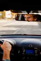 Free photo man driving a car seen through rearview mirror