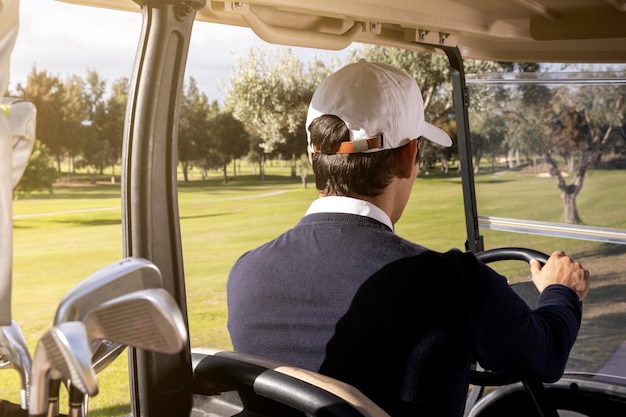 Foto gratuita uomo alla guida di golf cart sul campo