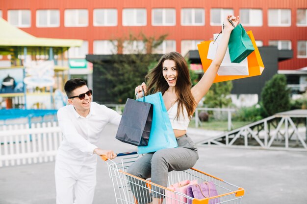 Man driving shopping cart with happy woman